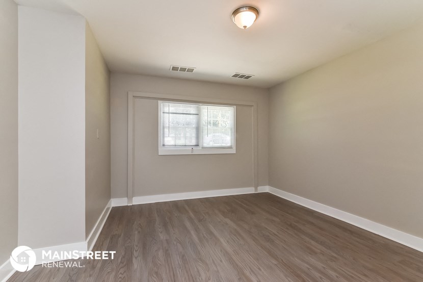 the living room of an apartment with wood flooring and a window