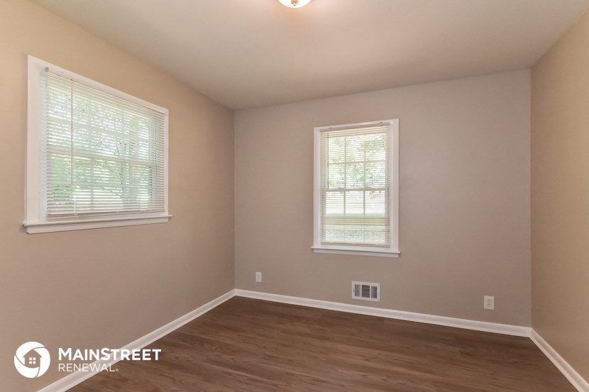 the interior of an empty room with wooden floors and two windows
