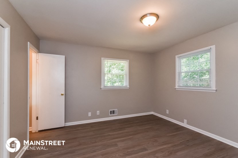 the interior of an empty room with a door and two windows