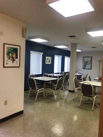 The-Oaks-Community2 community room with tables and chairs by large windows