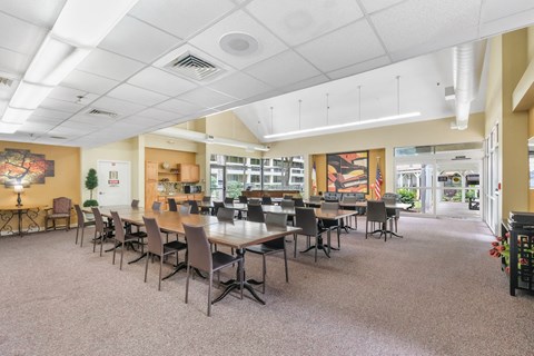 large community room with tables, chairs, and piano