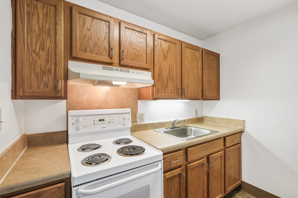 Sundale-Kitchen1 residential kitchen at Sundale Manor Apartments with white appliances and wood cabinetry