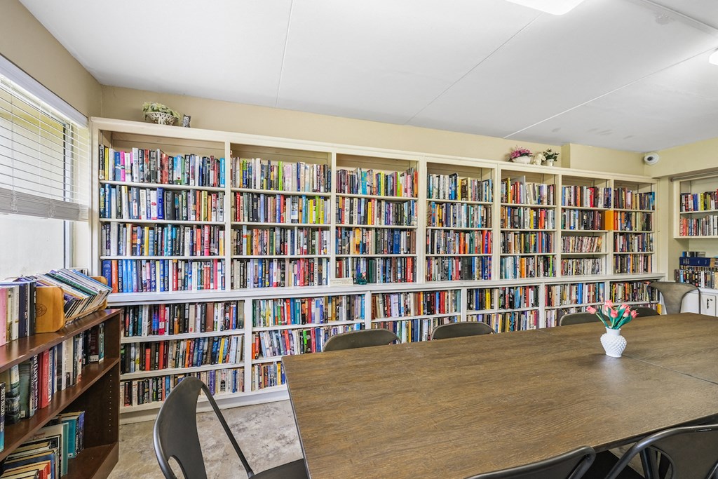 entire wall full of book shelves with books and reading table in library