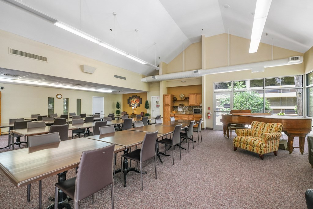 Sundale-Community-Room1 community room with rows of tables and chairs and a piano at Sundale Manor Apartments