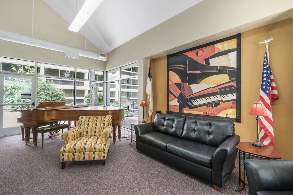 community room with large painting, couch, chairs, American flag, and piano