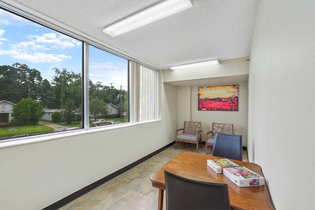 alcove with large windows, chairs, table, and puzzles
