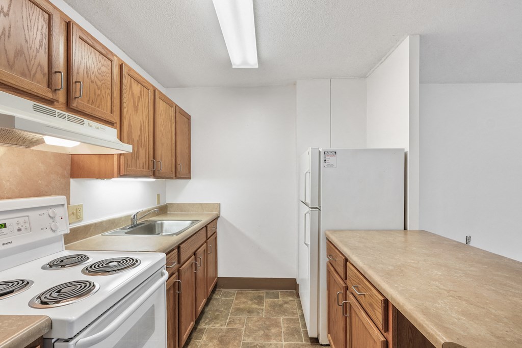 kitchen with stove, fridge, ample wood cabinets, bar, and overhead lighting