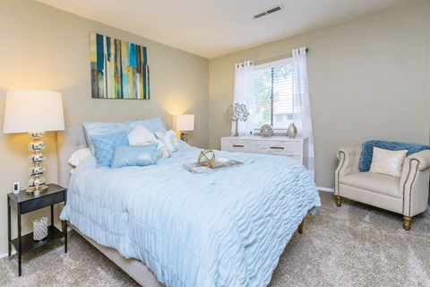 a bedroom with a bed and a chair and a window