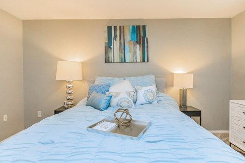 a bedroom with a bed with blue bedding and a tray
