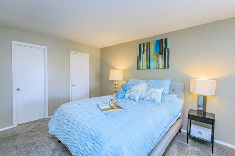 a bedroom with a blue bed and a painting on the wall