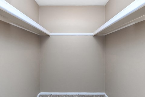 a walk in closet in a home with beige walls and a white ceiling