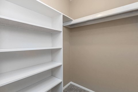 a walk in closet in a home with empty shelves