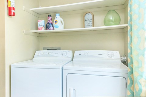 a white washer and dryer in a small laundry room with a shelf above