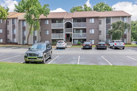 a parking lot with cars in front of an apartment building