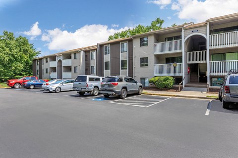 a parking lot with cars in front of an apartment building