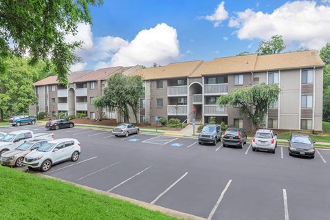an empty parking lot with cars in front of an apartment building