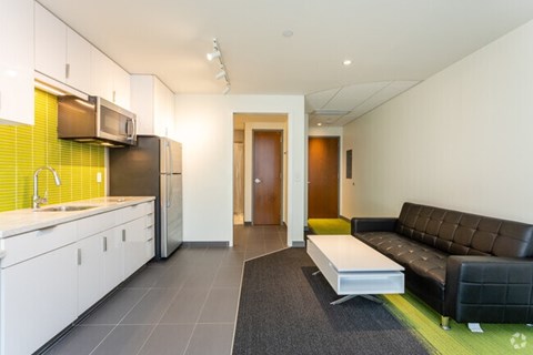 A modern kitchen with a black couch and a bench.