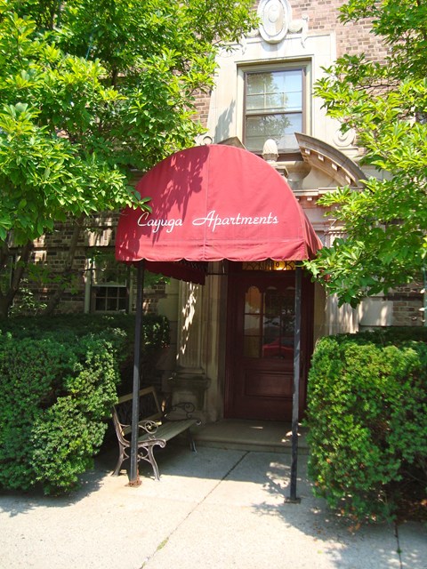 A red awning with the words Cayuga Apartments on it.