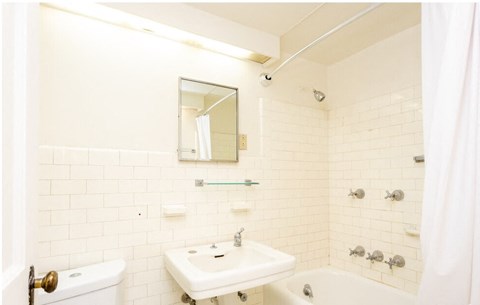 A white bathroom with a sink, mirror, and bathtub.