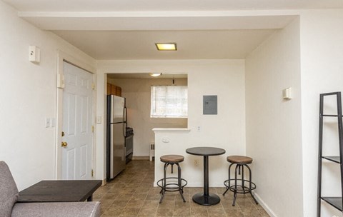 A kitchen area with a refrigerator, a table and a couch.