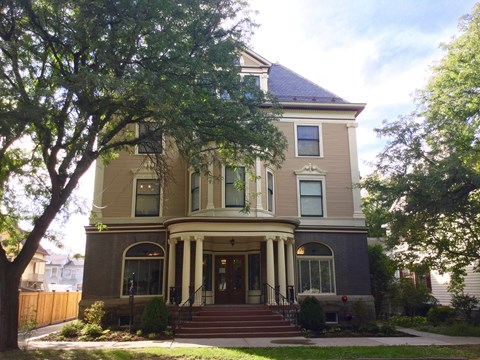 A large house with a front porch and a tree in front.
