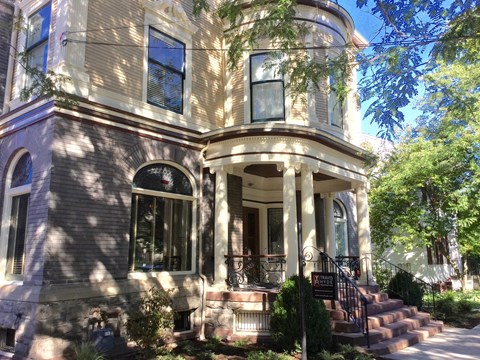 A Victorian style house with a front porch and stairs leading up to the entrance.