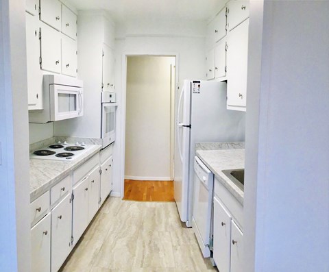 A kitchen with white cabinets and appliances.