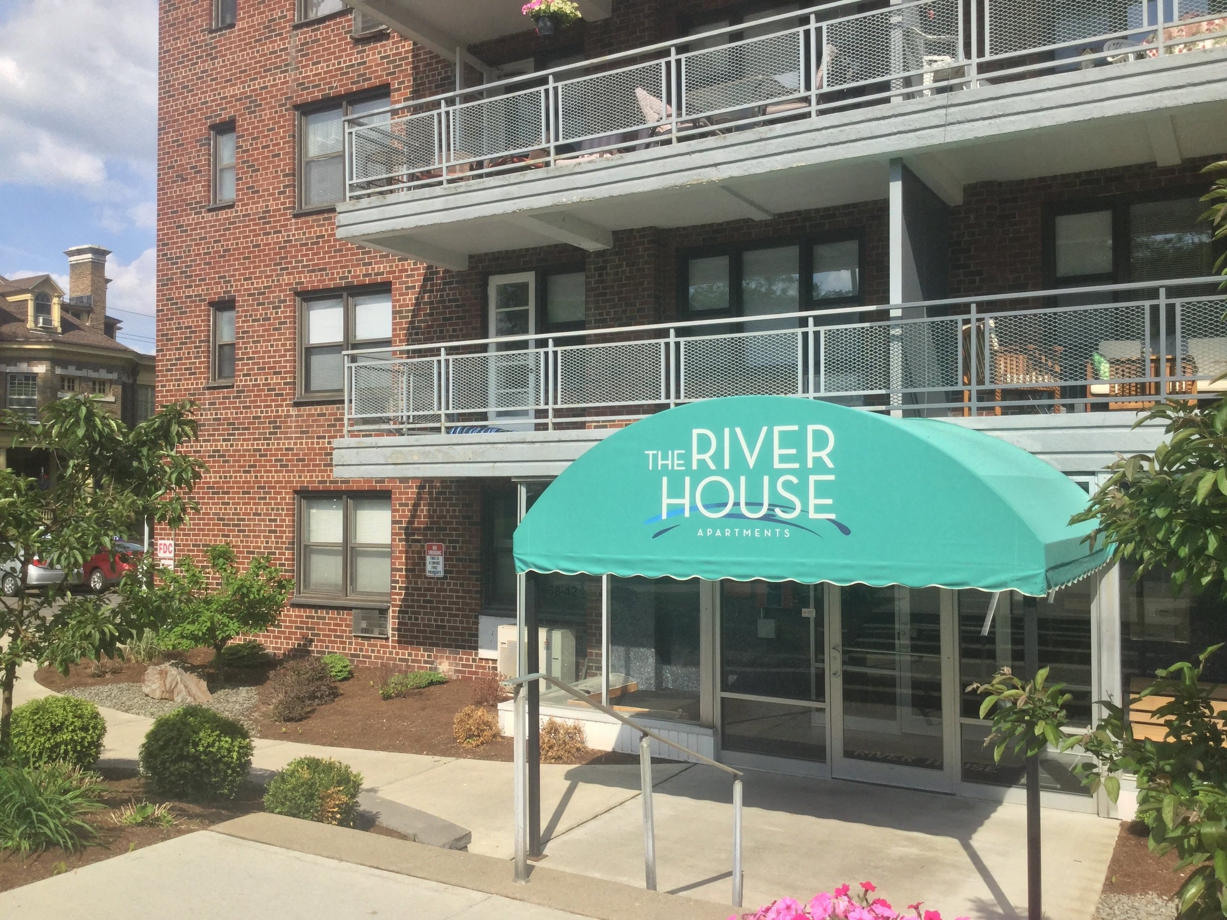 A building with a balcony and a green awning that says "The River House".