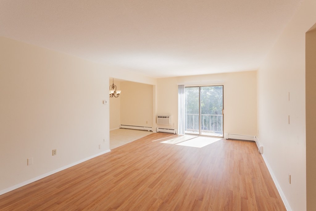 an empty living room with wood floors and a sliding glass door