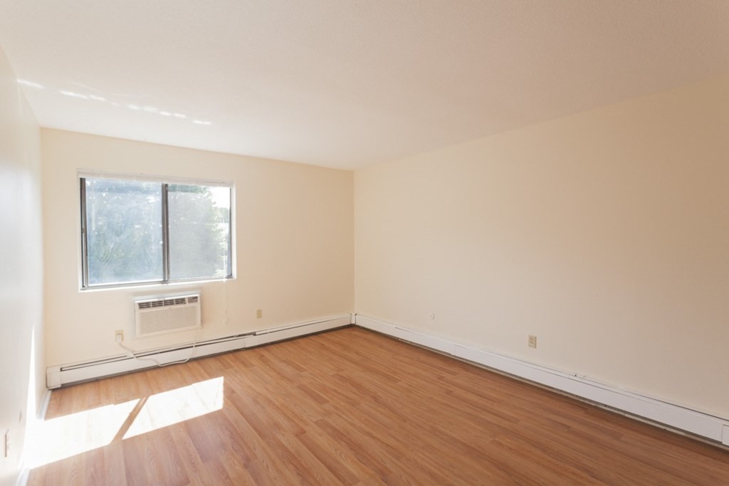 an empty room with wooden floors and a window