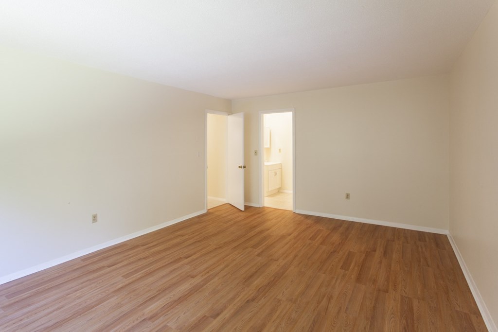 an empty living room with wood floors and white walls