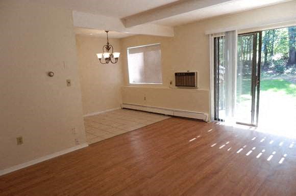 an empty living room with a wood floor and a sliding glass door