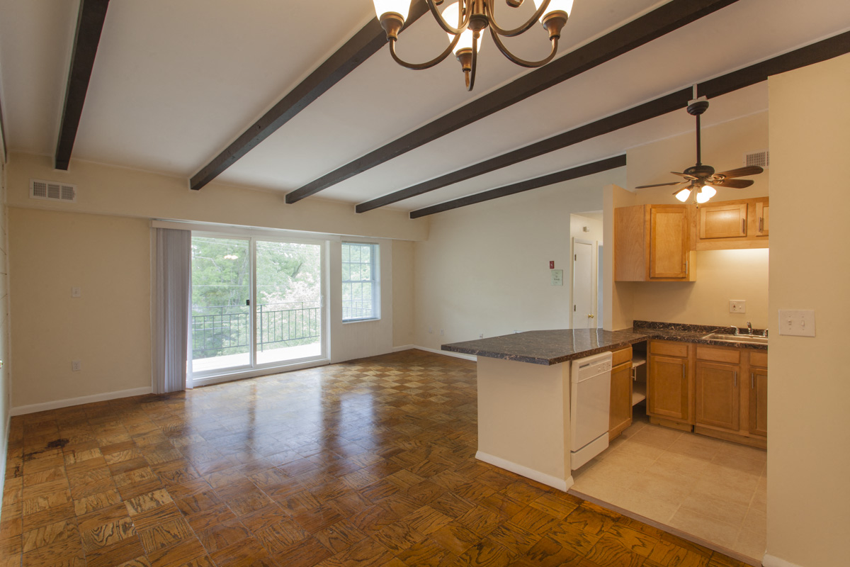 an empty living room with a kitchen and a sliding glass door