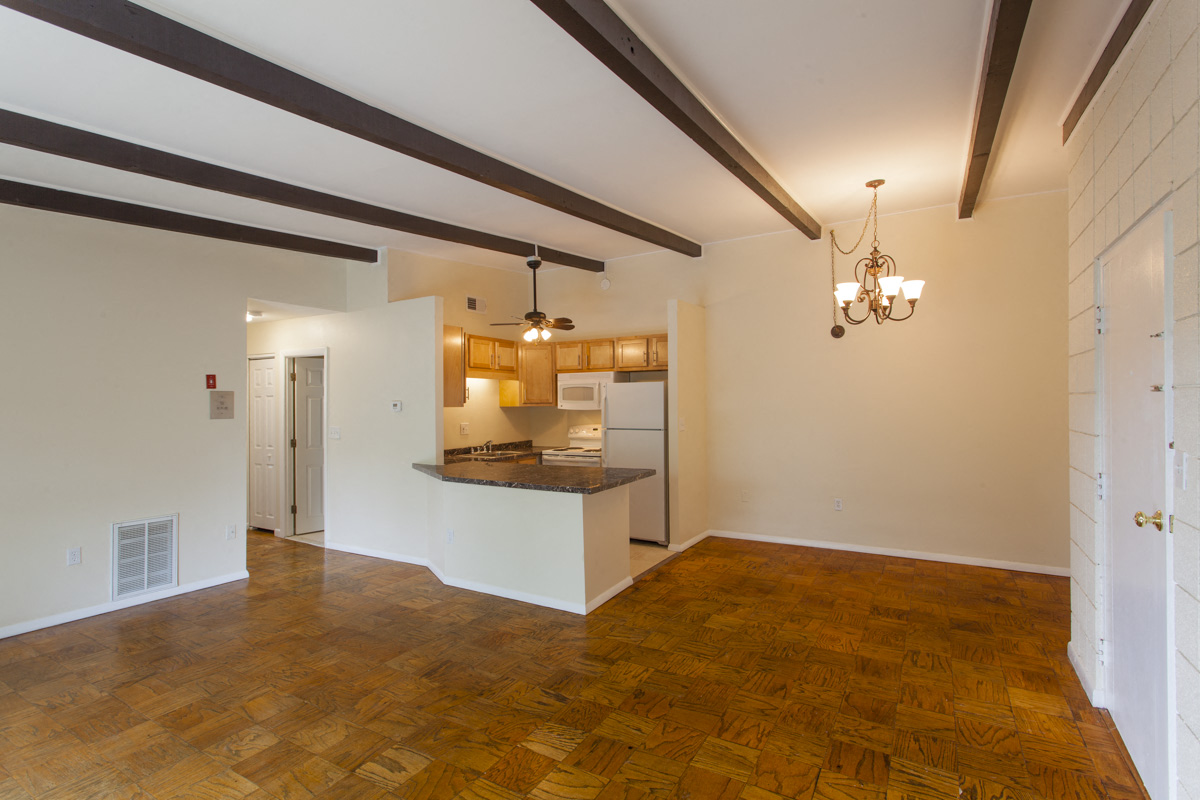 the living room and kitchen of an empty house with wood flooring