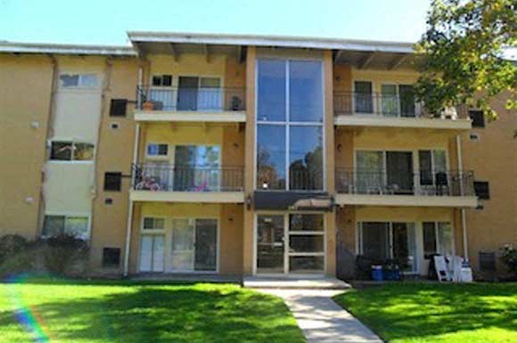 a yellow apartment building with a lawn in front