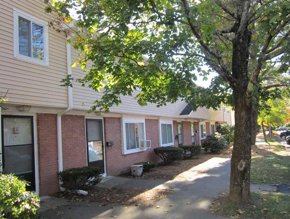 the exterior of a brick apartment building with a sidewalk and trees