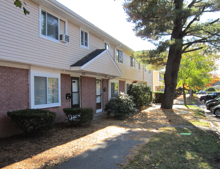 a side view of a building with a sidewalk and trees