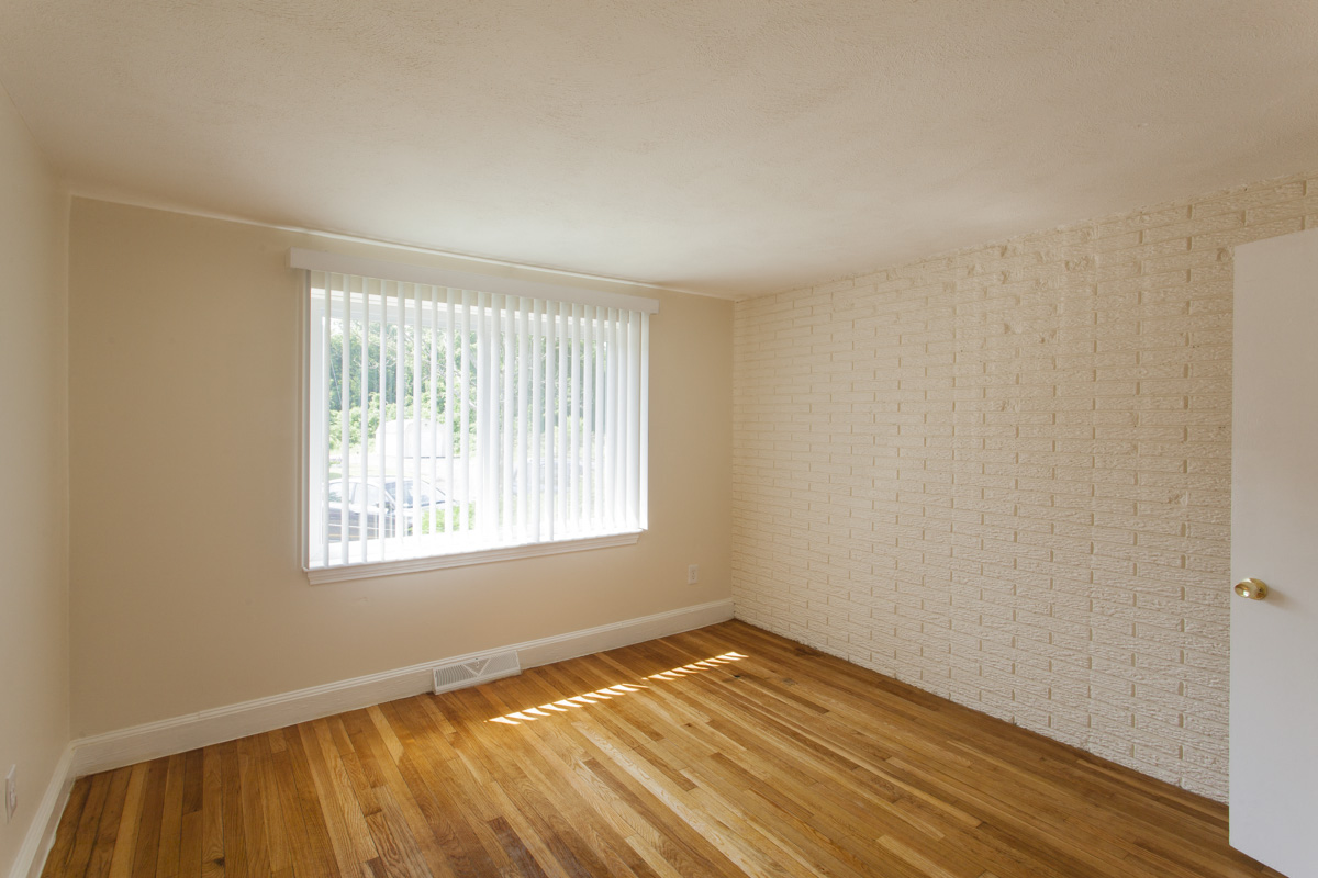 an empty living room with wood floors and a window