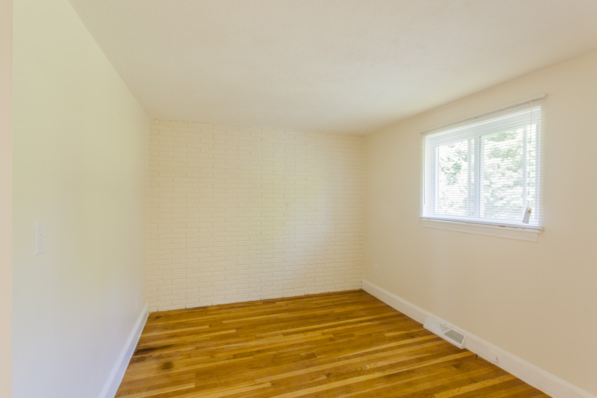 an empty room with wooden floors and a window