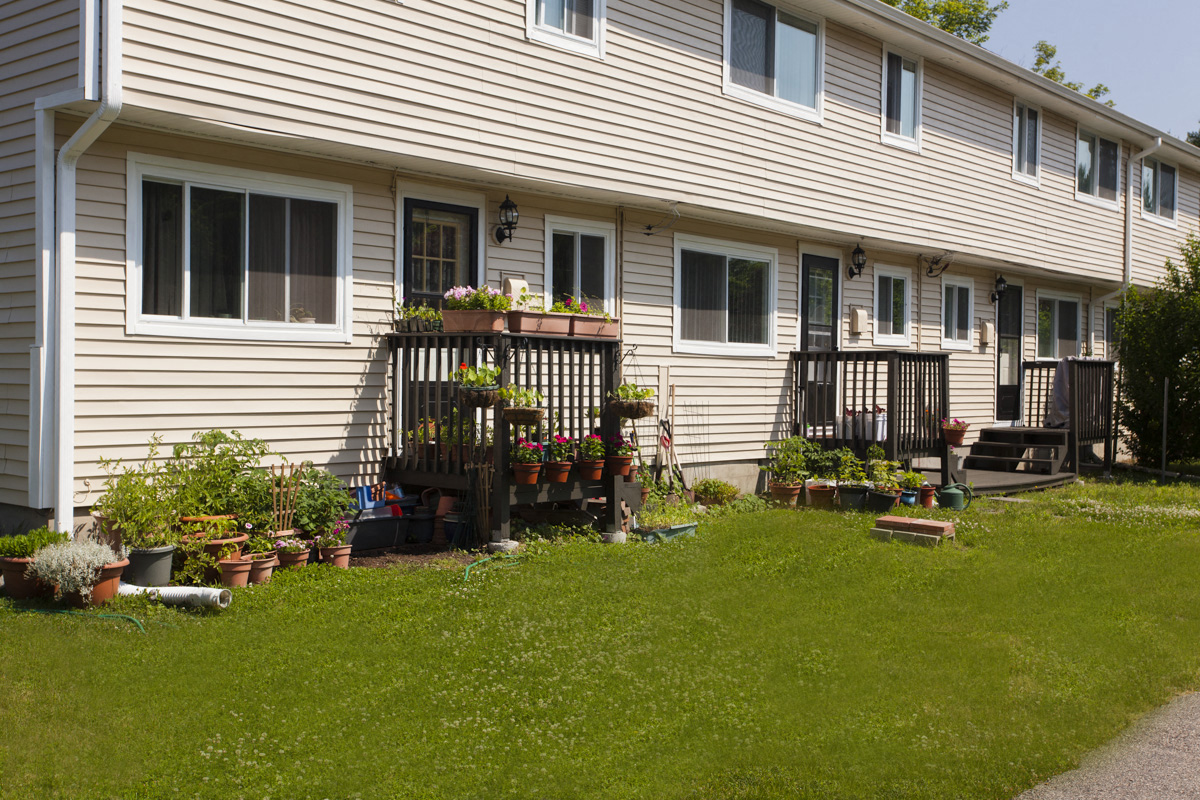 the side of a house with potted plants in the yard