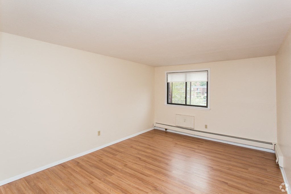an empty living room with wood flooring and a window