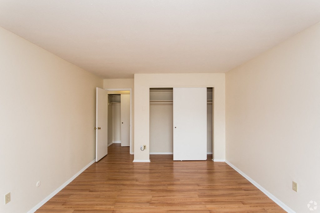 an empty living room with wood floors and white walls and closets