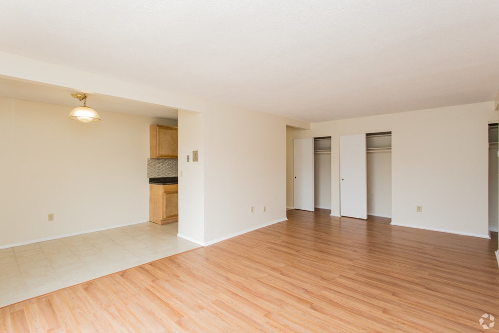 an empty living room with wood floors and white walls