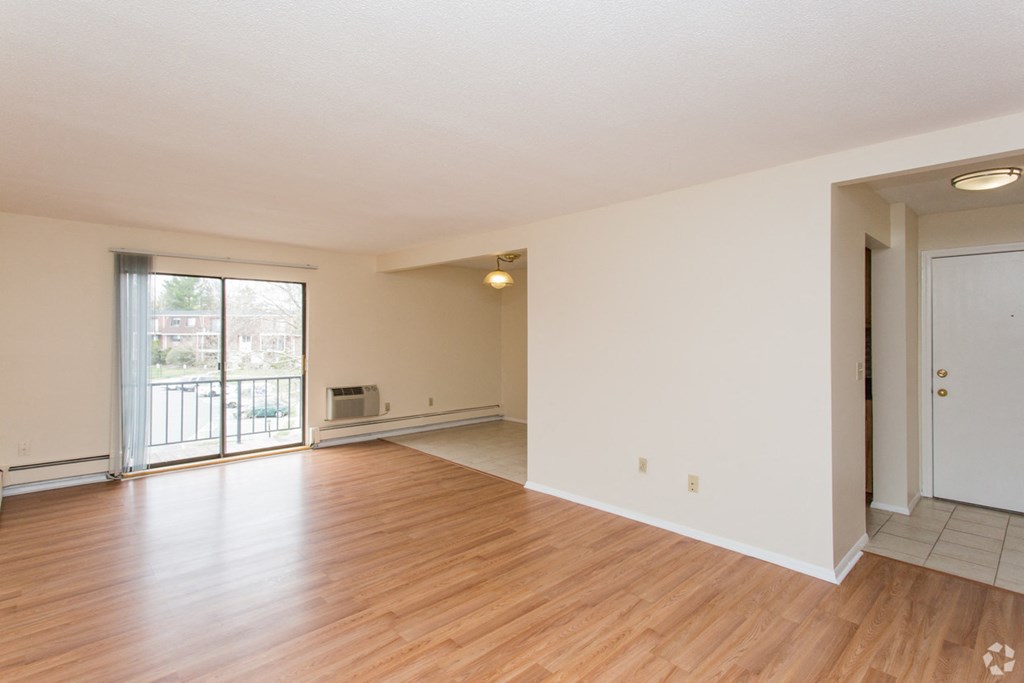 the living room and dining room of an empty house with wood floors and a door