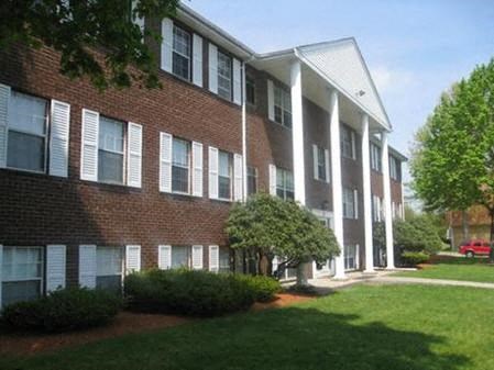 a brick apartment building with green grass and trees