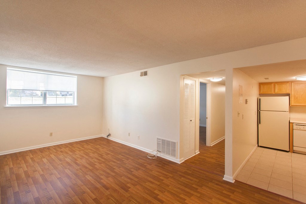 an empty living room and kitchen with a refrigerator and