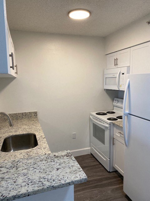 a kitchen with white appliances and granite counter tops