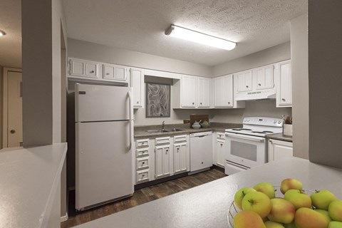 a kitchen with white cabinets and appliances and a bowl of fruit