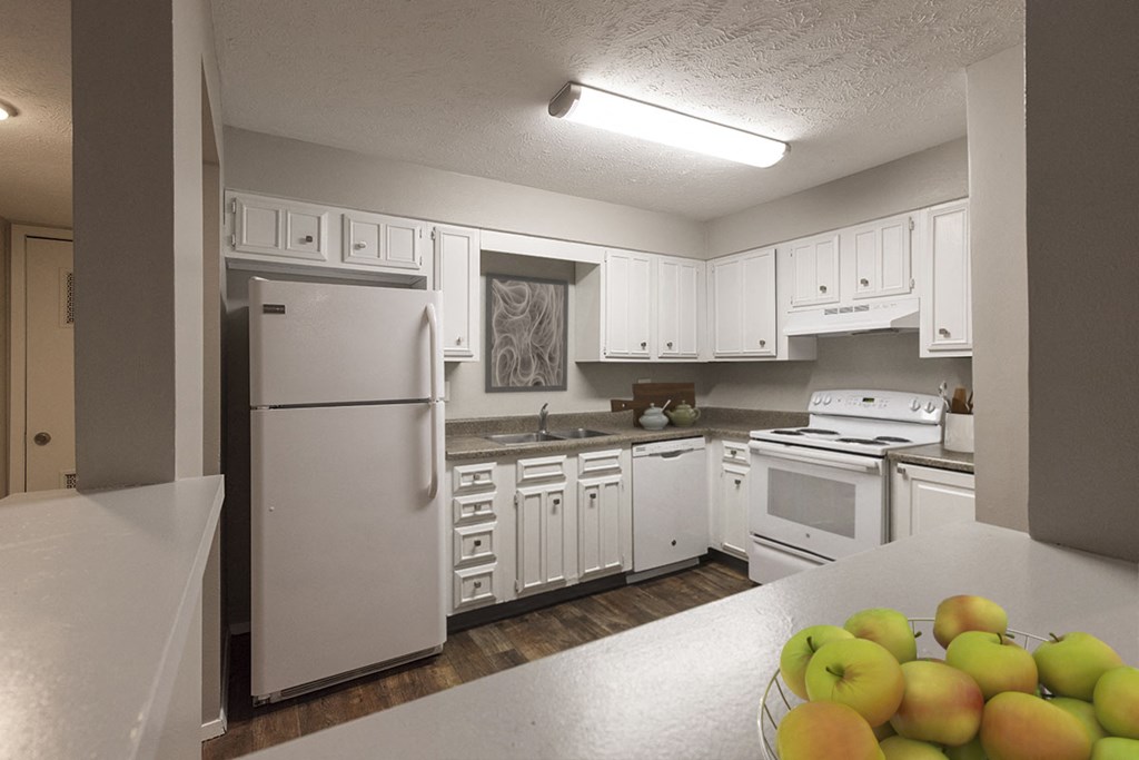 a kitchen with white cabinets and appliances and a bowl of fruit