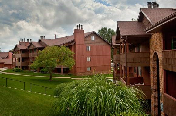 an apartment building with a lawn and trees
